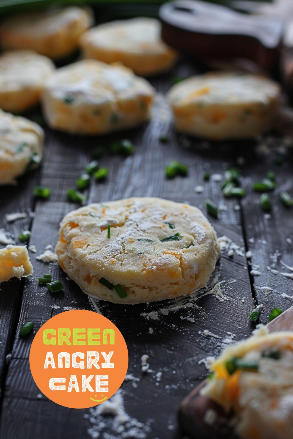 The process of making cheddar scallion biscuits, showing dough being folded on a dark, black wooden texture surface.