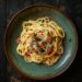 Top-down view of a Porchetta Carbonara dish on a red plate, showcasing creamy pasta with crispy bits of porchetta.