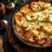 Top-down view of a baking dish filled with golden brown, cheesy scalloped potatoes on a dark, black wooden surface