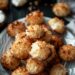 Top-down view of coconut macaroons on a white plate, set on a dark wooden surface.