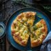 Crisp and fluffy sourdough focaccia on a dark wooden plate.