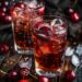 Two glasses of cherry vanilla soda, one with a splash of bourbon, garnished with fresh cherries and ice, placed on a dark wooden surface.