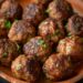 Top-down view of crispy sausage cheese balls on a blue plate, placed on a dark, black wooden texture surface.