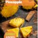 A vibrant photo showing a freshly cut pineapple on a chopping board, with the top and bottom removed, skin peeled, and the pineapple cut into quarters with the core removed. The background is a dark, black wooden texture surface. This image demonstrates pineapple cutting techniques.