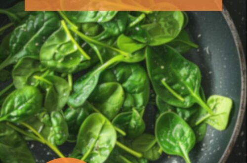 A vibrant photo showing freshly cooked spinach in a large frying pan, garnished with a sprinkle of salt and black pepper. The background is a dark, black wooden texture surface. This image demonstrates spinach preparation techniques.